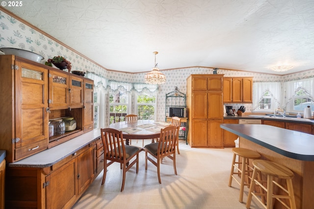 dining space featuring a chandelier, wallpapered walls, a wealth of natural light, vaulted ceiling, and ornamental molding
