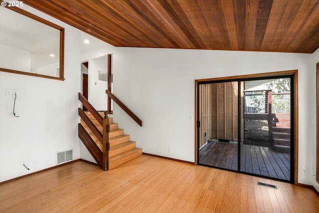 interior space with vaulted ceiling, visible vents, baseboards, and hardwood / wood-style flooring