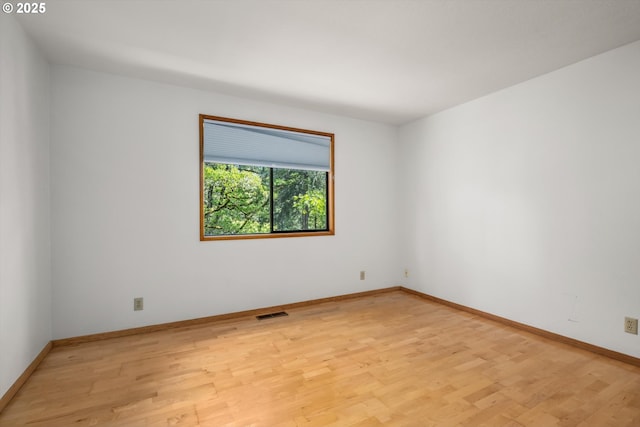 empty room with baseboards, light wood-type flooring, and visible vents