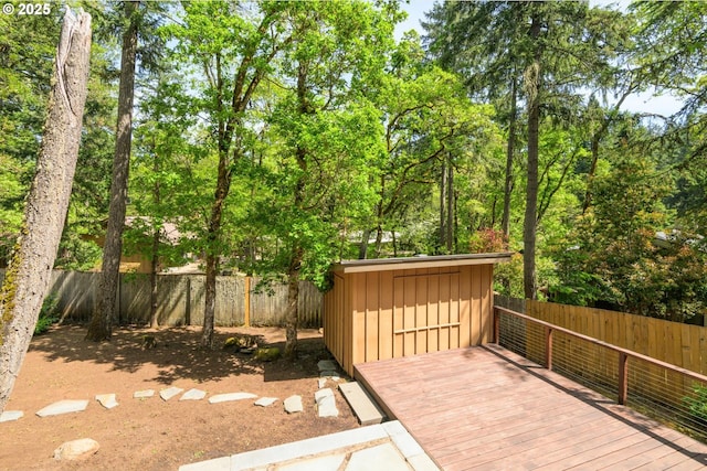 wooden deck featuring a fenced backyard, an outdoor structure, and a shed