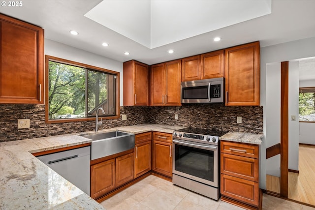 kitchen with stainless steel appliances, recessed lighting, a sink, and light stone counters