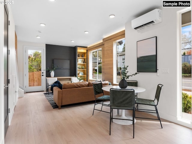 dining area with recessed lighting, a wall mounted air conditioner, and light wood-style flooring
