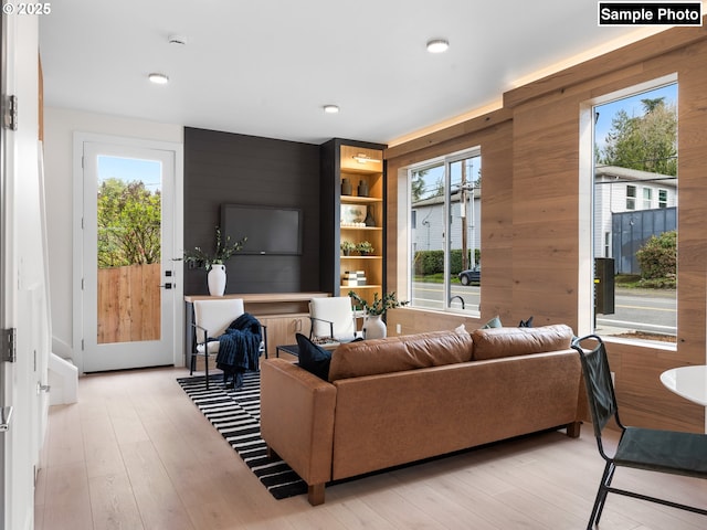 living area with light wood-style floors, recessed lighting, and wood walls