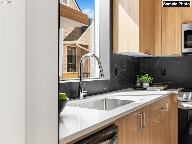 kitchen featuring modern cabinets, tasteful backsplash, a sink, light countertops, and stainless steel appliances