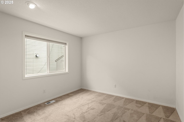 spare room featuring carpet, a textured ceiling, visible vents, and baseboards