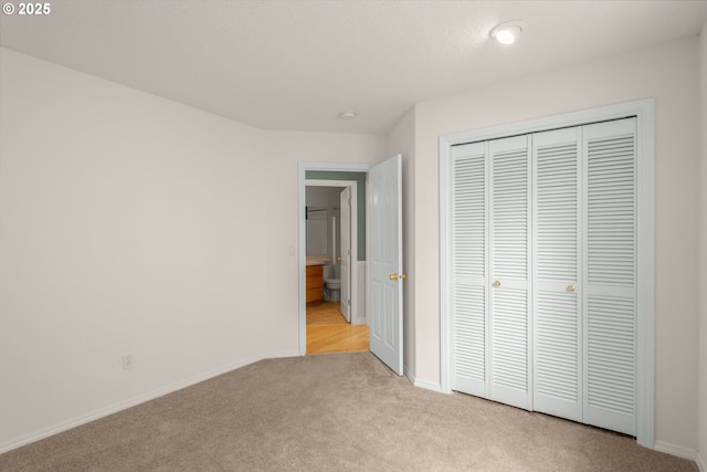 unfurnished bedroom featuring light carpet, a closet, and baseboards