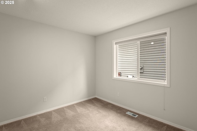 carpeted spare room featuring visible vents and baseboards