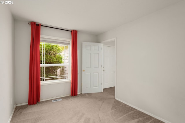 carpeted empty room featuring visible vents and baseboards