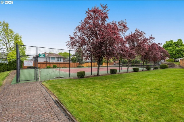 view of tennis court featuring a yard, fence, and a gate