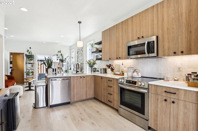 kitchen with light countertops, a peninsula, a wealth of natural light, and stainless steel appliances