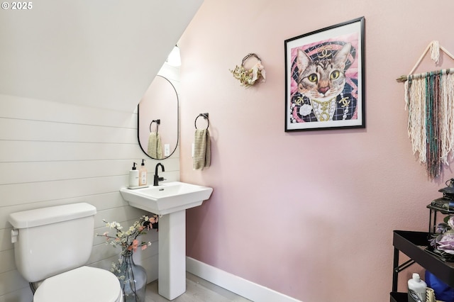 bathroom featuring baseboards, vaulted ceiling, and toilet