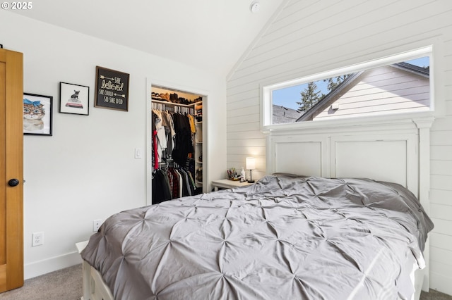 carpeted bedroom with a spacious closet, a closet, wood walls, and lofted ceiling