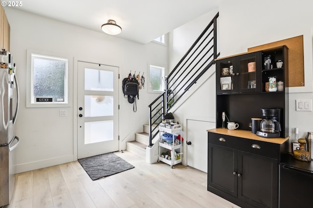 entrance foyer with baseboards, light wood-style flooring, and stairs