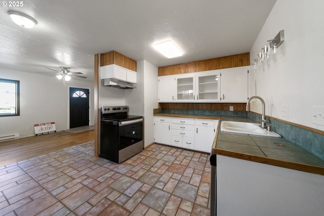 kitchen with stainless steel electric range oven, sink, white cabinets, ceiling fan, and baseboard heating