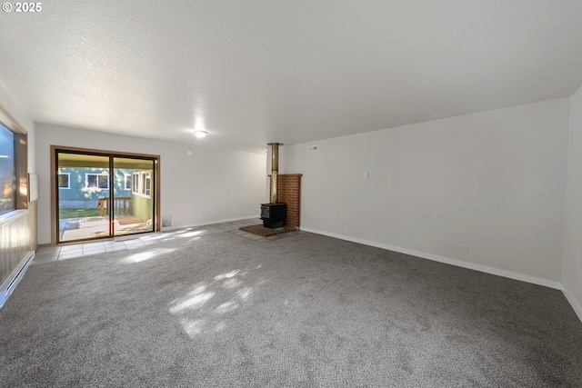 unfurnished living room featuring a wood stove, light carpet, and a textured ceiling