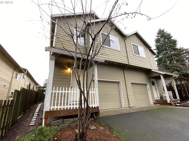 view of front of property featuring driveway, covered porch, a garage, and fence