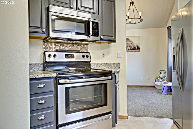 425 Warner St, Oregon City, OR 97045 - kitchen with stainless steel appliances, a chandelier, light carpet, light stone countertops, and baseboards