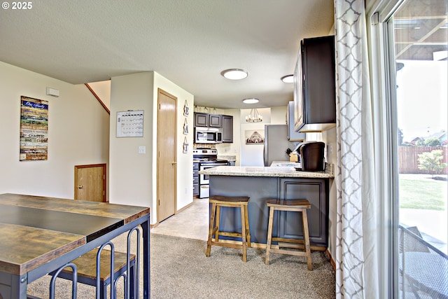 425 Warner St, Oregon City, OR 97045 - kitchen featuring appliances with stainless steel finishes, light colored carpet, a peninsula, and a kitchen bar