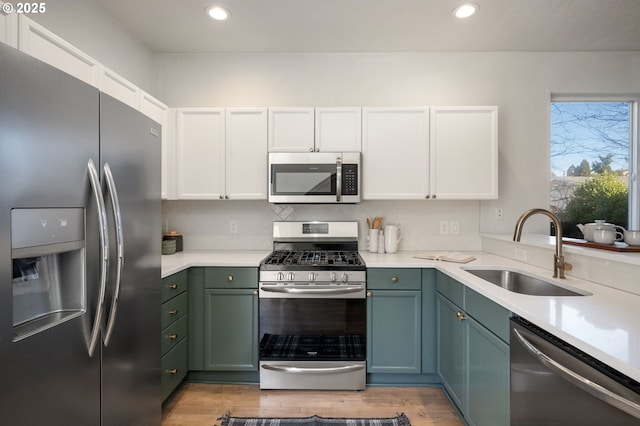 kitchen featuring a sink, stainless steel appliances, light countertops, green cabinets, and backsplash