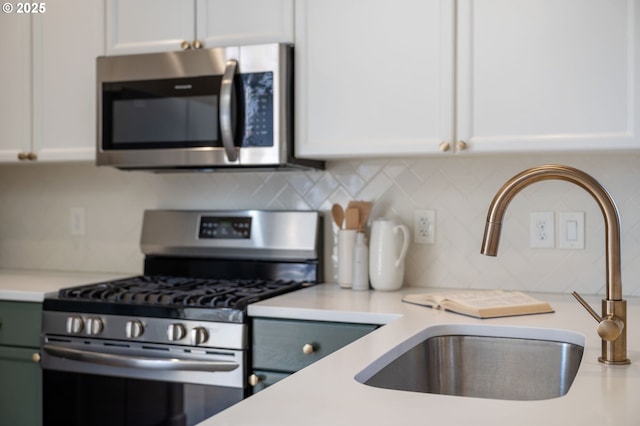 kitchen featuring stainless steel appliances, light countertops, white cabinets, and a sink