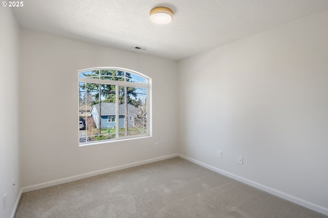 carpeted empty room with visible vents, a textured ceiling, and baseboards