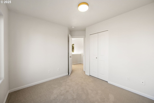 unfurnished bedroom with a closet, baseboards, and carpet flooring