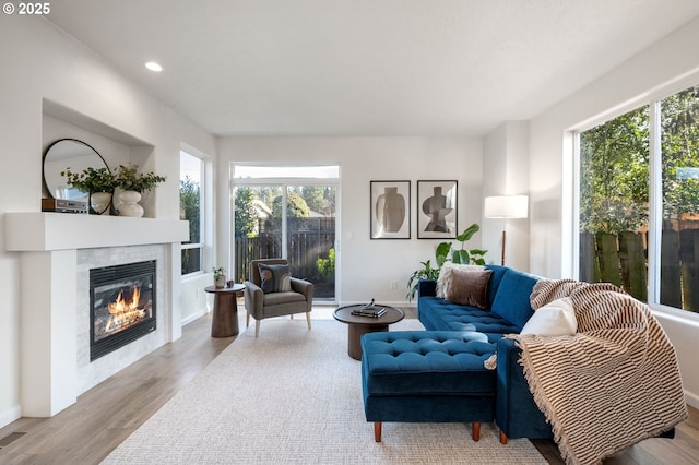 living area featuring baseboards, a tile fireplace, wood finished floors, and recessed lighting