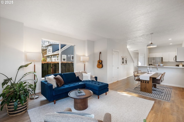 living area with light wood-type flooring, a textured ceiling, baseboards, and recessed lighting