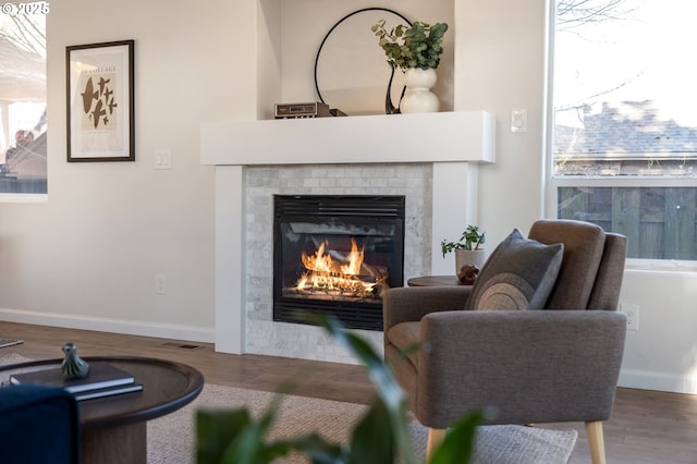 living area featuring visible vents, a fireplace, baseboards, and wood finished floors