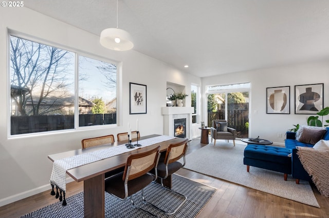 dining room with wood finished floors, recessed lighting, a glass covered fireplace, and baseboards