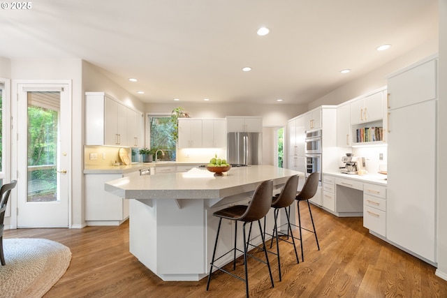 9030 SW Lancelot Ln, Portland, OR 97219 - kitchen with stainless steel appliances, plenty of natural light, a breakfast bar, a center island, and recessed lighting
