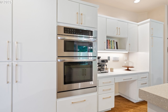 kitchen with double oven, light wood-type flooring, white cabinets, open shelves, and recessed lighting