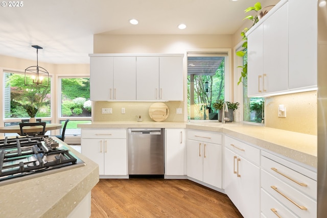 kitchen with stainless steel appliances, tasteful backsplash, light wood finished floors, recessed lighting, and white cabinets