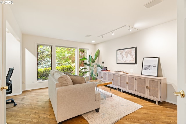 living room with track lighting, light wood-type flooring, and baseboards