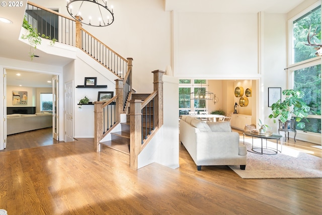 9030 SW Lancelot Ln, Portland, OR 97219 - living area featuring a towering ceiling, a chandelier, stairs, plenty of natural light, and wood finished floors
