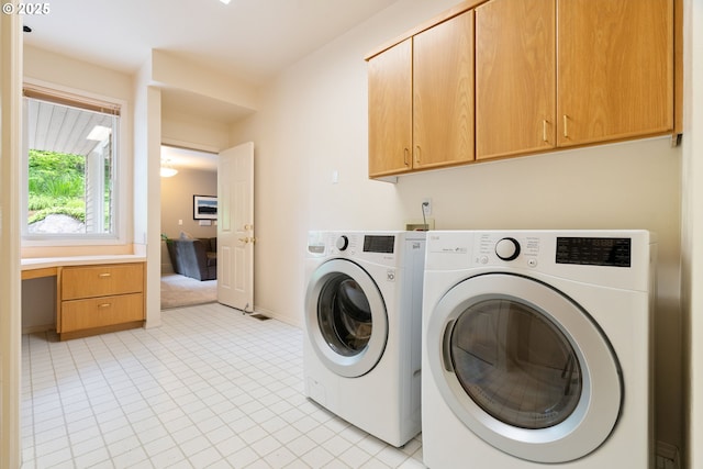 laundry area with separate washer and dryer, cabinet space, light tile patterned floors, and baseboards