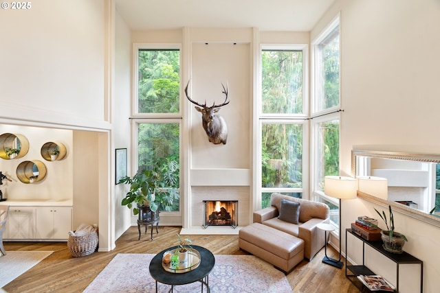 9030 SW Lancelot Ln, Portland, OR 97219 - living room featuring a fireplace with flush hearth, wood finished floors, and a towering ceiling