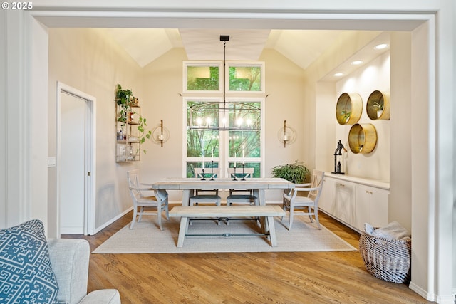 dining area featuring lofted ceiling, light wood-style flooring, a chandelier, and baseboards