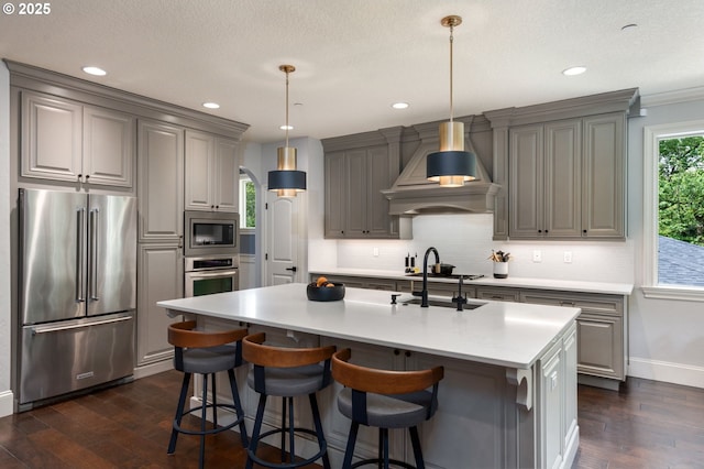 kitchen with gray cabinets, stainless steel appliances, dark wood-style flooring, and wall chimney exhaust hood