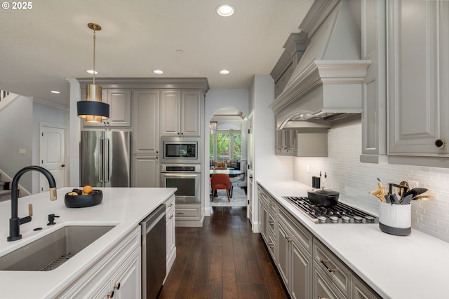 kitchen with appliances with stainless steel finishes, a sink, arched walkways, recessed lighting, and custom exhaust hood