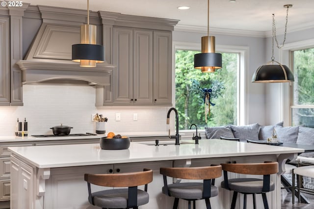 kitchen with gray cabinetry, cooktop, backsplash, and a sink