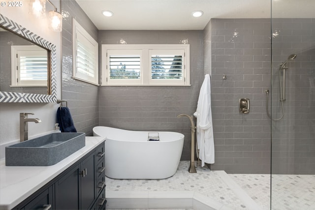 bathroom featuring a walk in shower, a freestanding tub, tile walls, and vanity