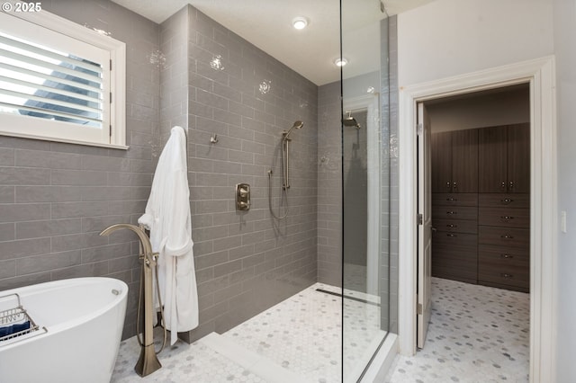 bathroom with a soaking tub, tile walls, and tiled shower