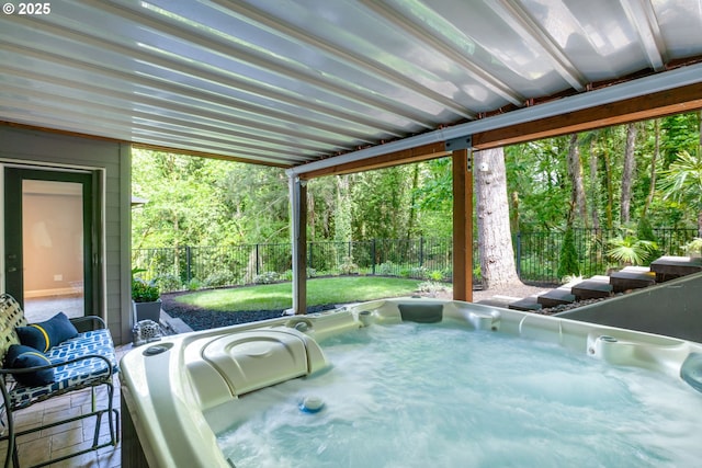 view of patio / terrace featuring a fenced backyard, a view of trees, and a hot tub