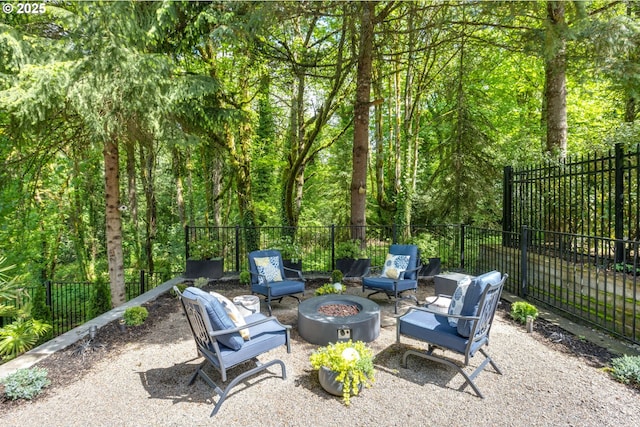 view of patio featuring fence, a fire pit, and a wooded view
