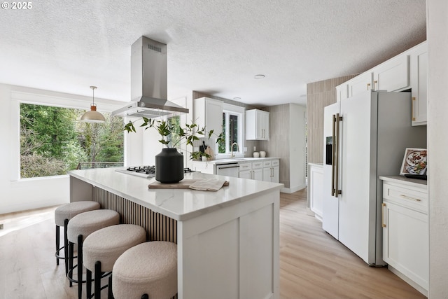 8616 SW 49th Ave, Portland, OR 97219 - kitchen with island exhaust hood, white refrigerator with ice dispenser, dishwasher, a breakfast bar, and light wood-style floors