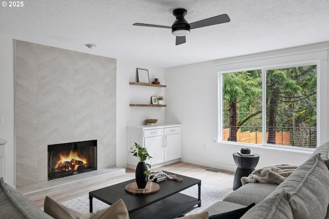 8616 SW 49th Ave, Portland, OR 97219 - living room with healthy amount of natural light, light wood-type flooring, ceiling fan, a tiled fireplace, and a textured ceiling