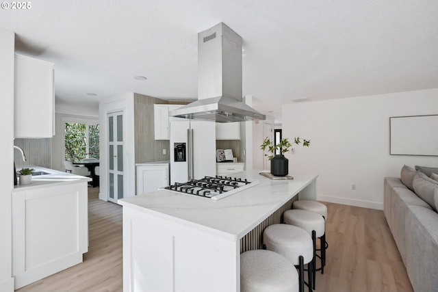 8616 SW 49th Ave, Portland, OR 97219 - kitchen featuring island range hood, white appliances, a sink, light wood-style floors, and white cabinetry