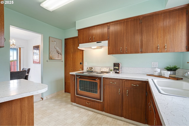 17725 NE Multnomah Dr, Portland, OR 97230 - kitchen featuring under cabinet range hood, stainless steel range with electric stovetop, a sink, light countertops, and brown cabinets