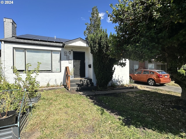 view of front of home with solar panels and a front yard